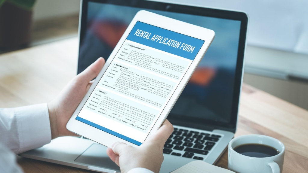 Image of a person holding a tablet with a rental application form on the screen