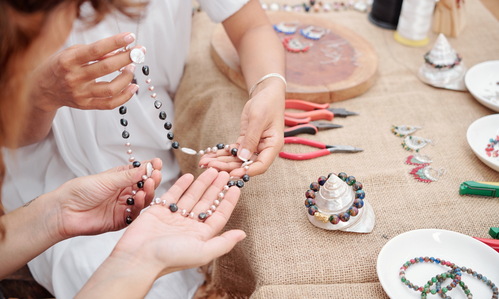 A close up image of two people jewelry making at an art workshop