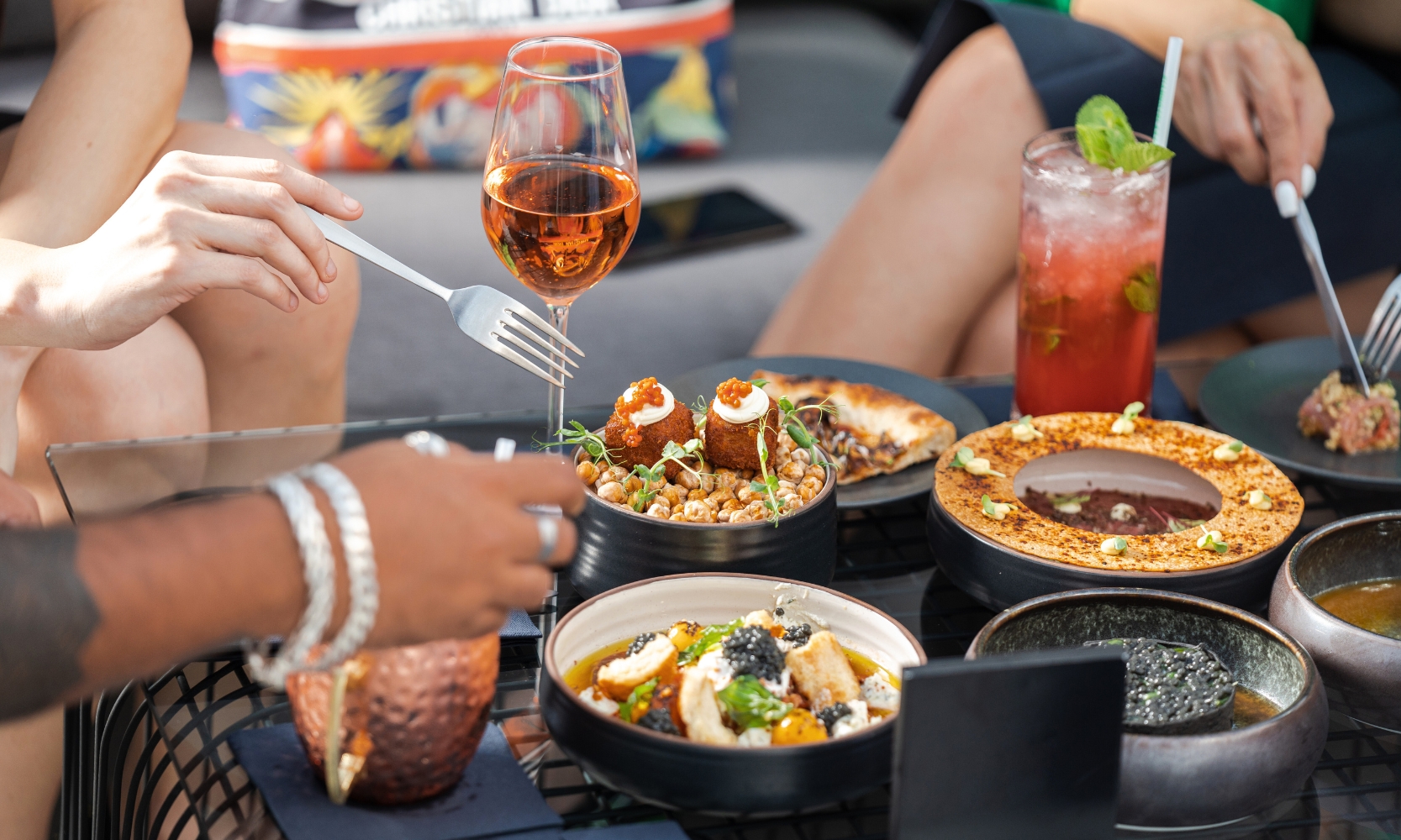 Close up image of people eating at a restaurant table with food and drinks