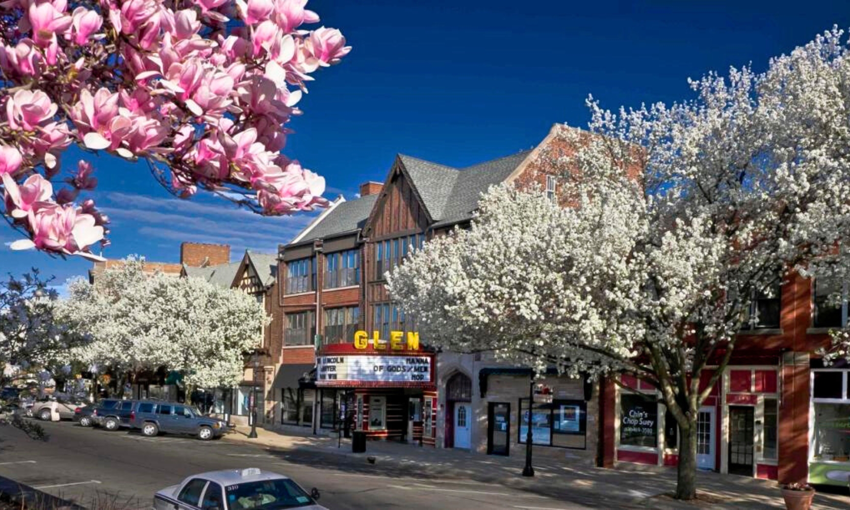 Image of downtown Glen Ellyn, IL, during spring with blooming trees and a movie theatre