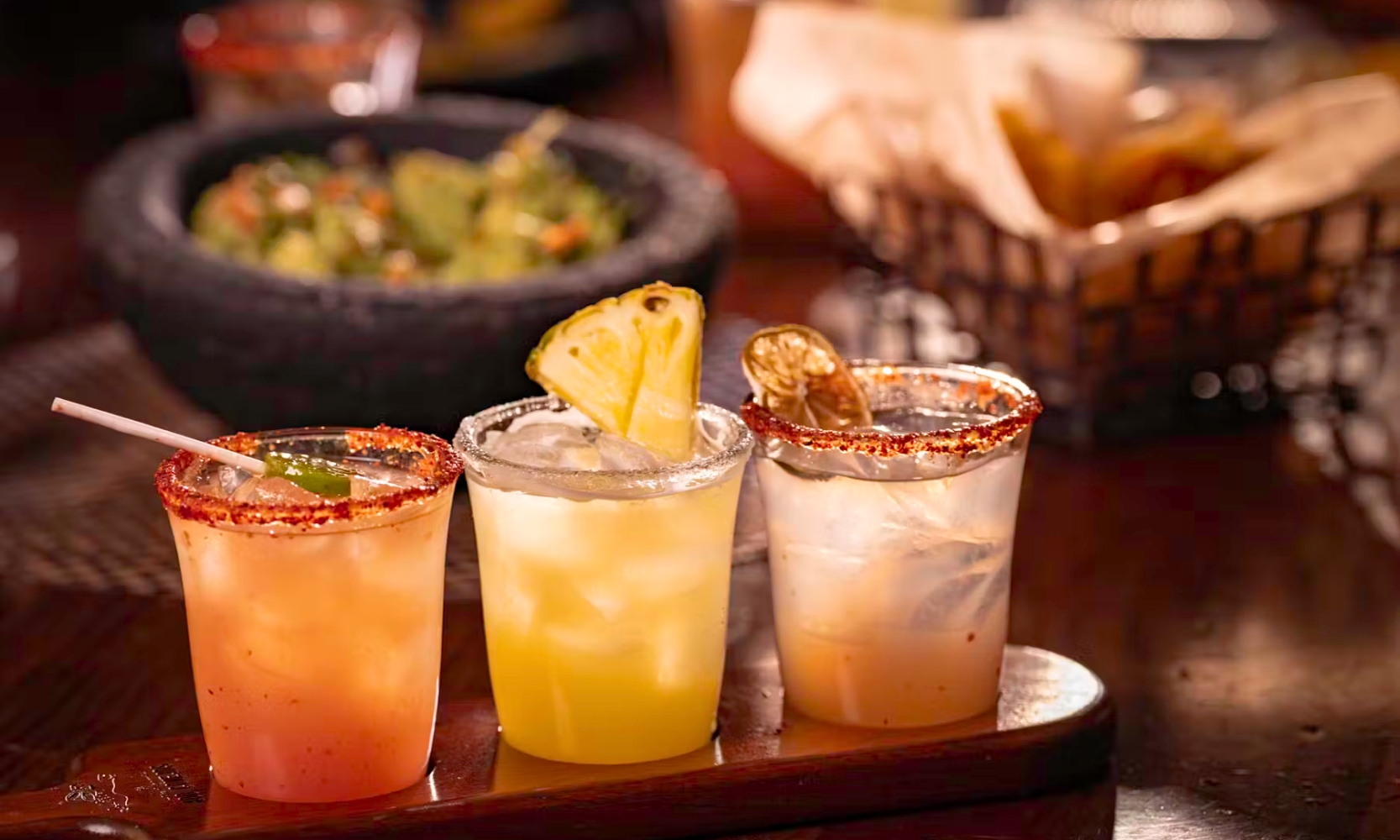 Image of three cocktails with guacamole and chips in the background at Mago Grill & Cantina in Arlington Heights, IL