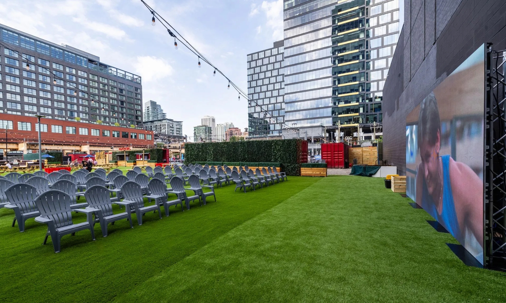 Wide shot image of The Garden at Fulton Market with a movie playing and empty chairs during the day