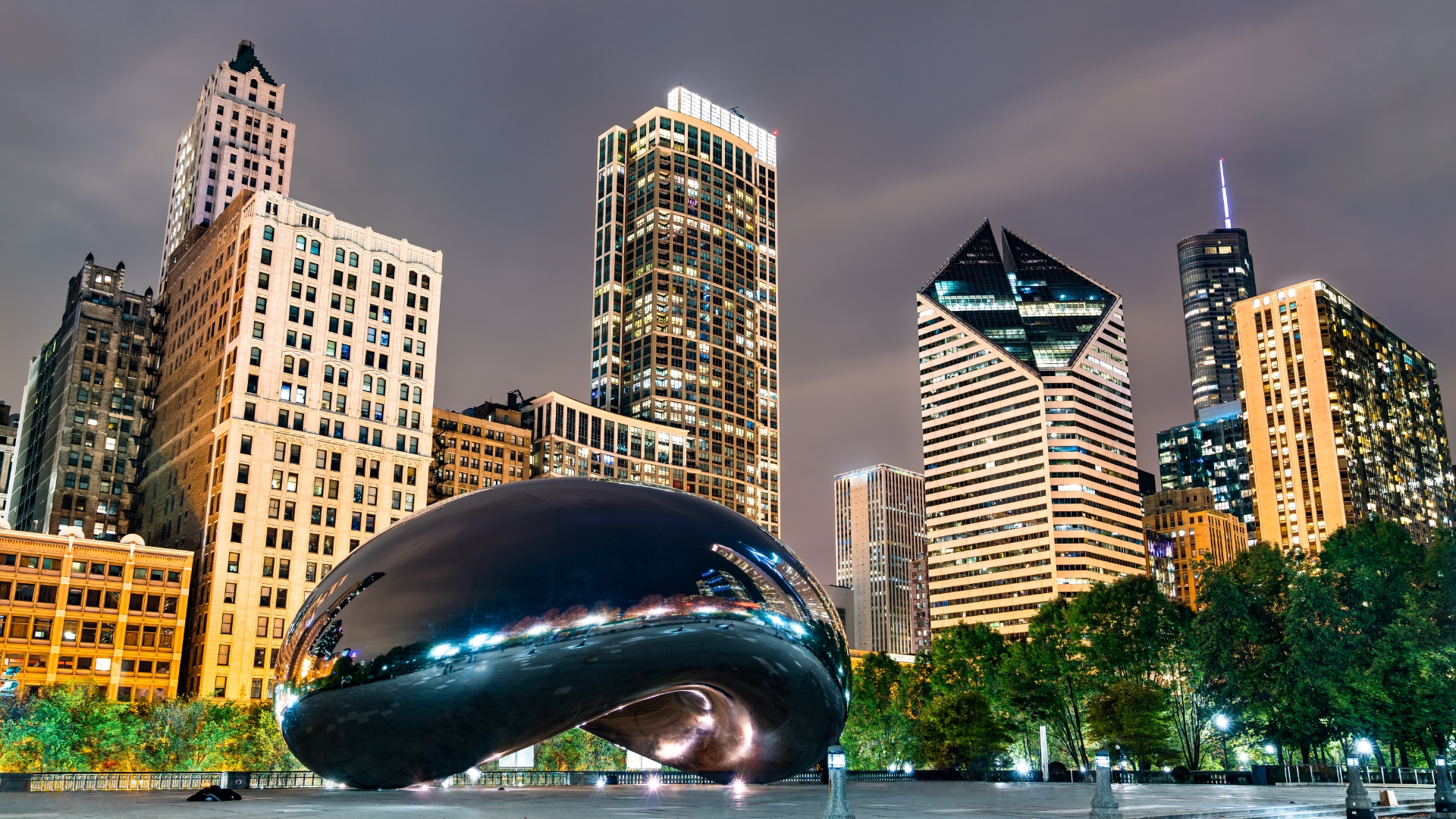 Image of the Cloud Gate "Bean" at night with skyscrapers in the background at Millennium Park, Chicago