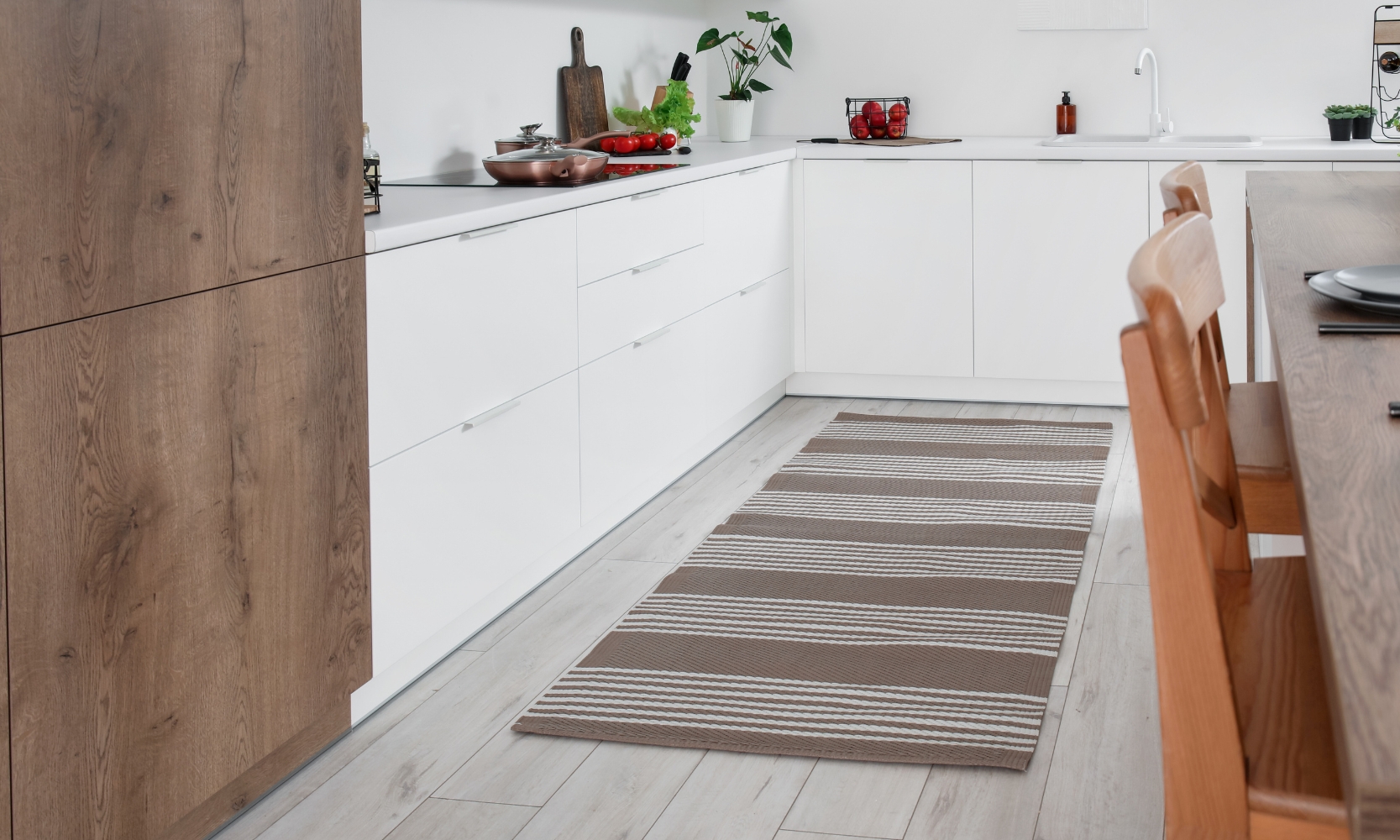 Image of a brown and white striped kitchen runner rug next to a dining table and cabinetry