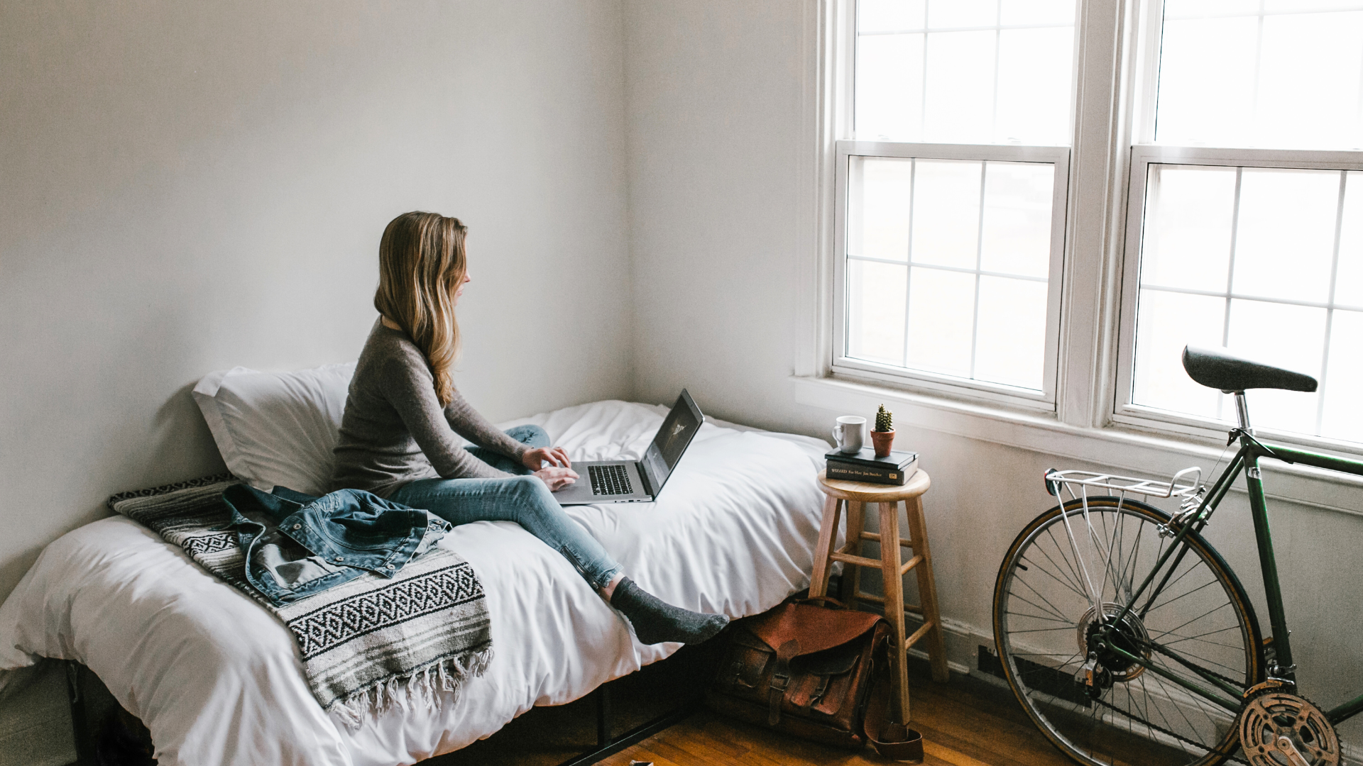 A profile view image of a young woman on her laptop in an apartment
