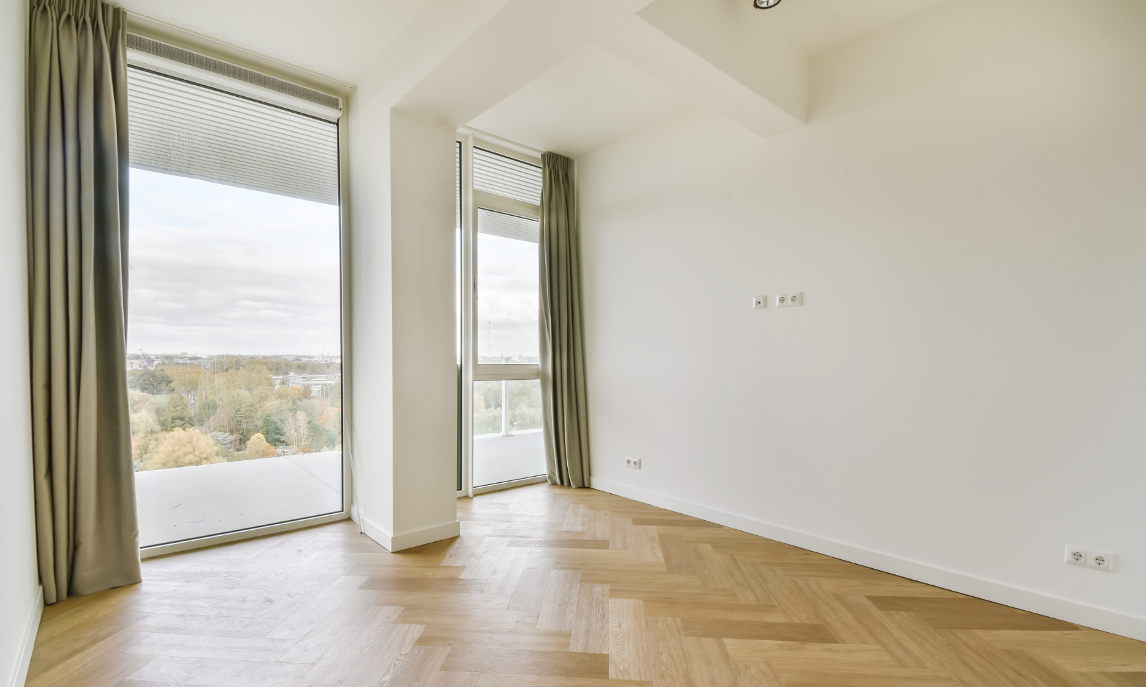 Image of an upper floor apartment with green floor to ceiling windows that are opened