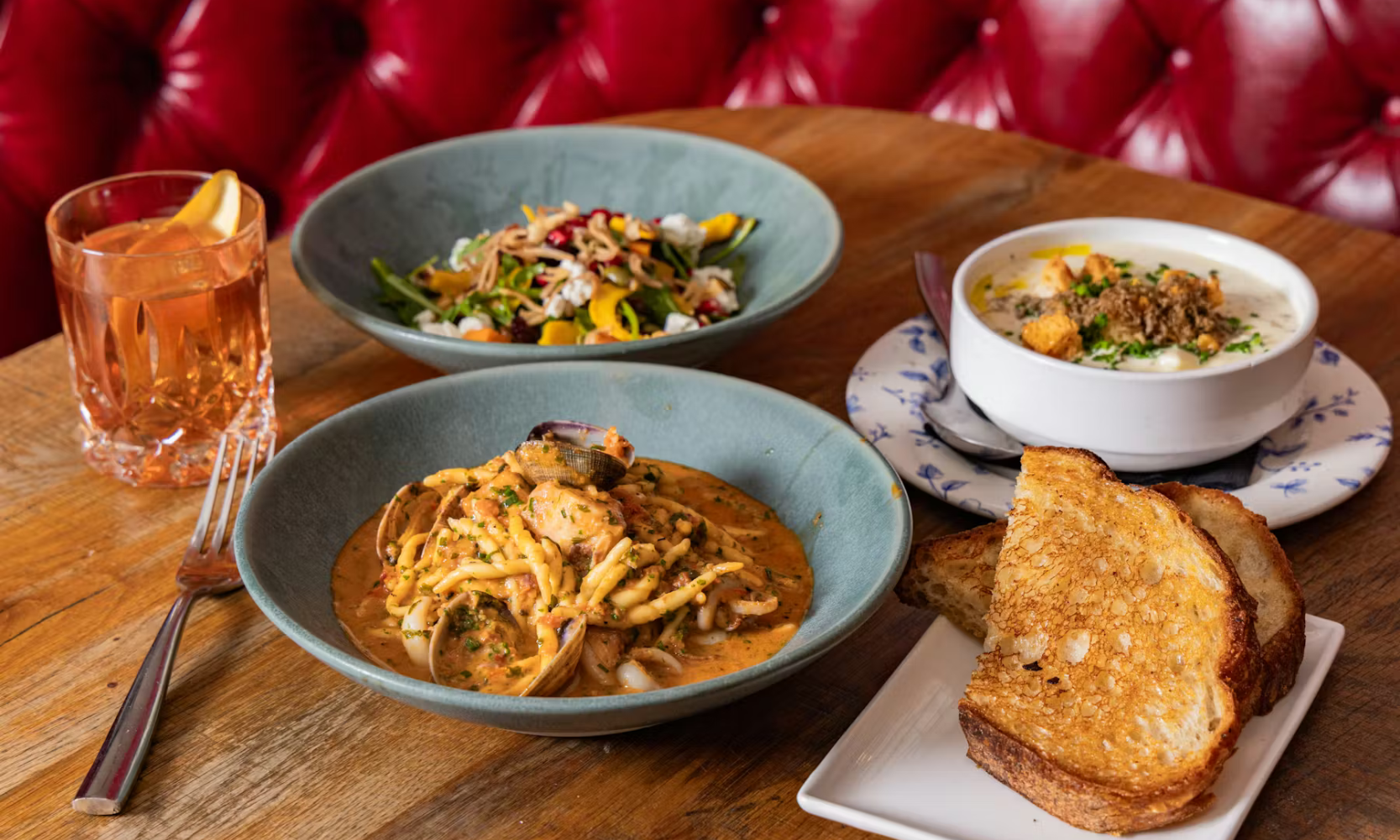 Closeup image dinner of multiple food dishes and a cocktail at The Dearborn in Chicago