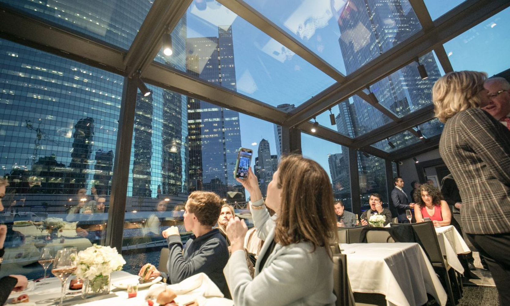 Interior image of people dining City Cruises dinner cruise looking at Chicago skyscrapers from inside the glass-enclosed vessel