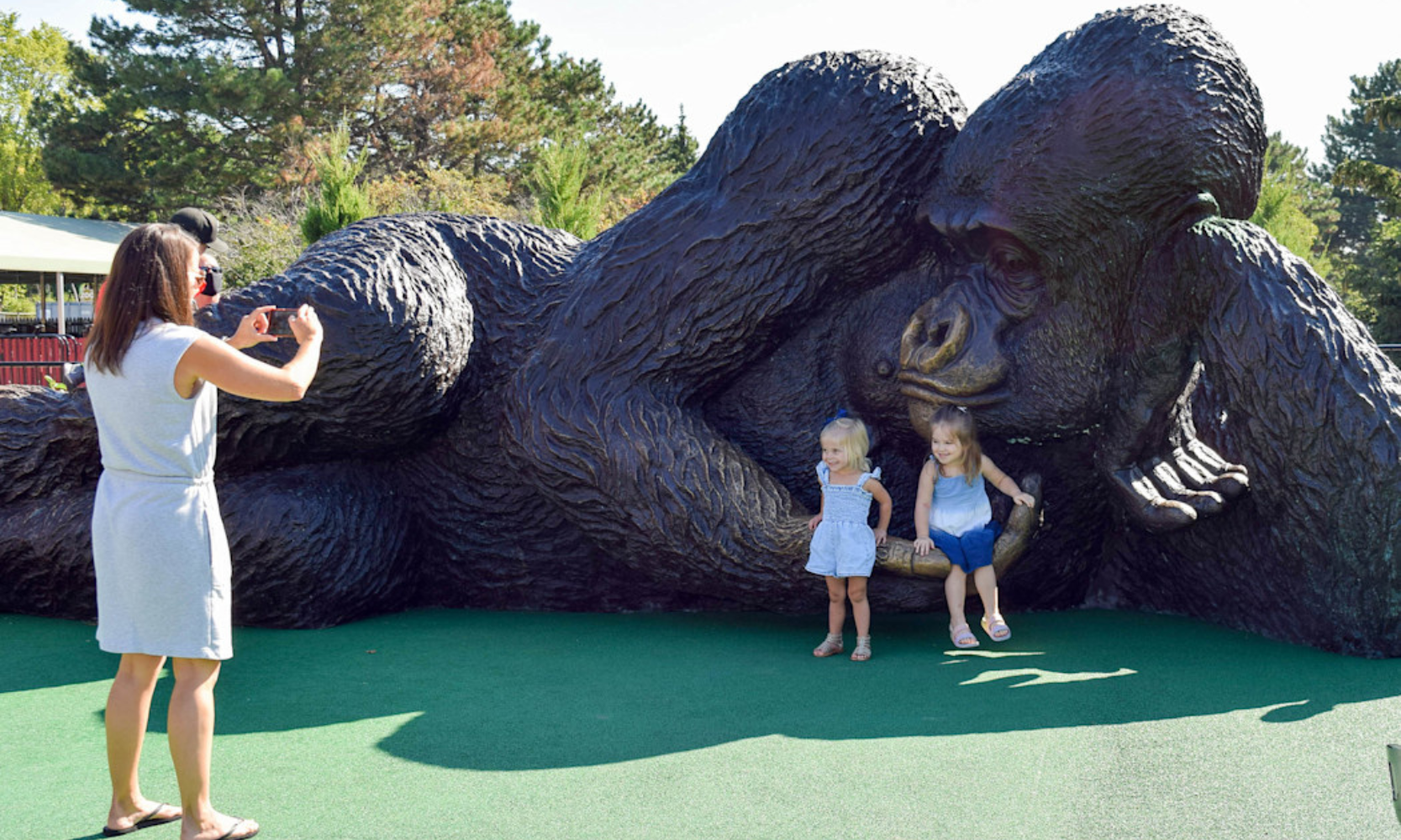 Image of a woman taking photos of two young children in front of a gorilla stature at Brookfield Zoo Chicago