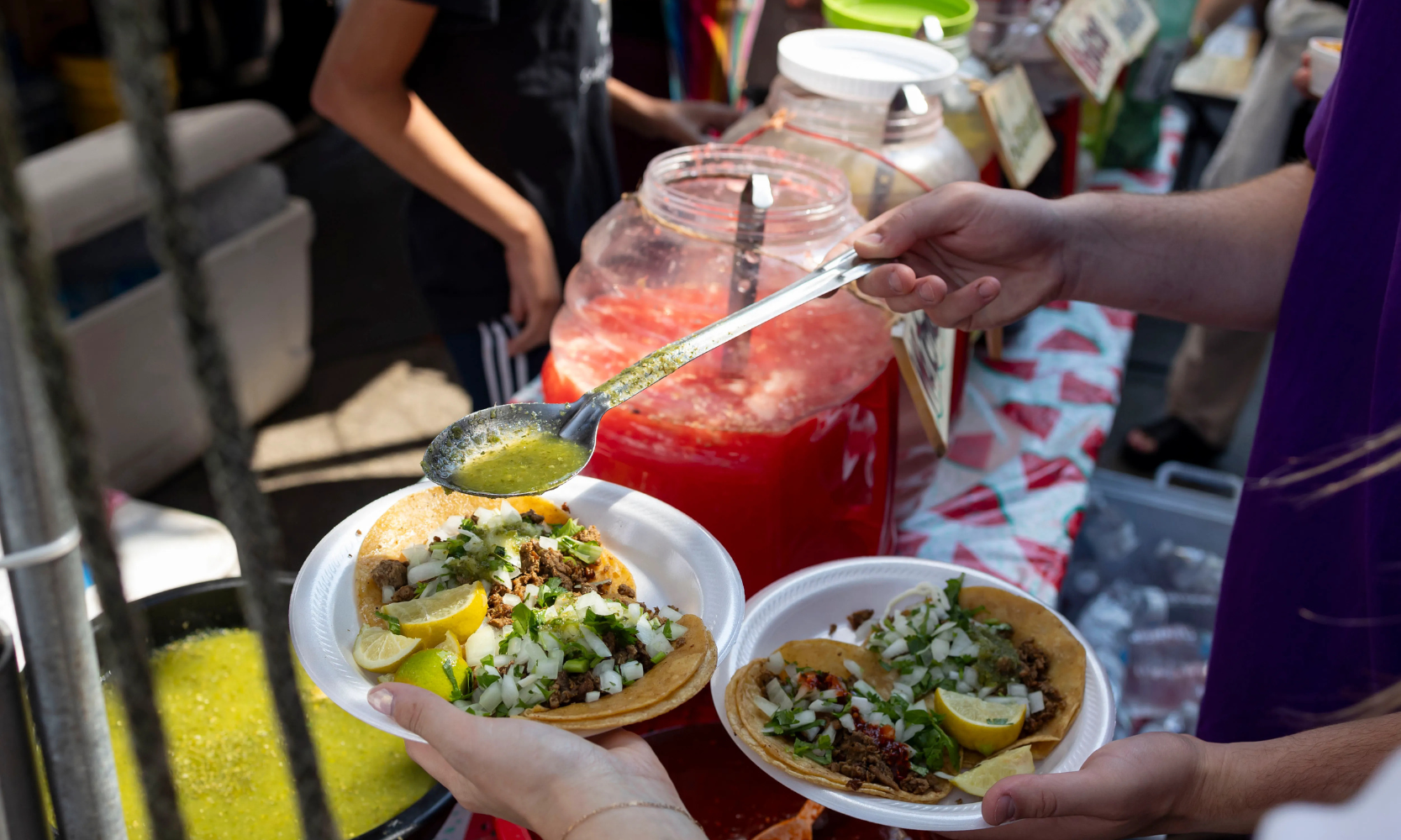 Close-up image of a person putting salsa verde on their tacos at the Lakeview Taco Fest in Chicago