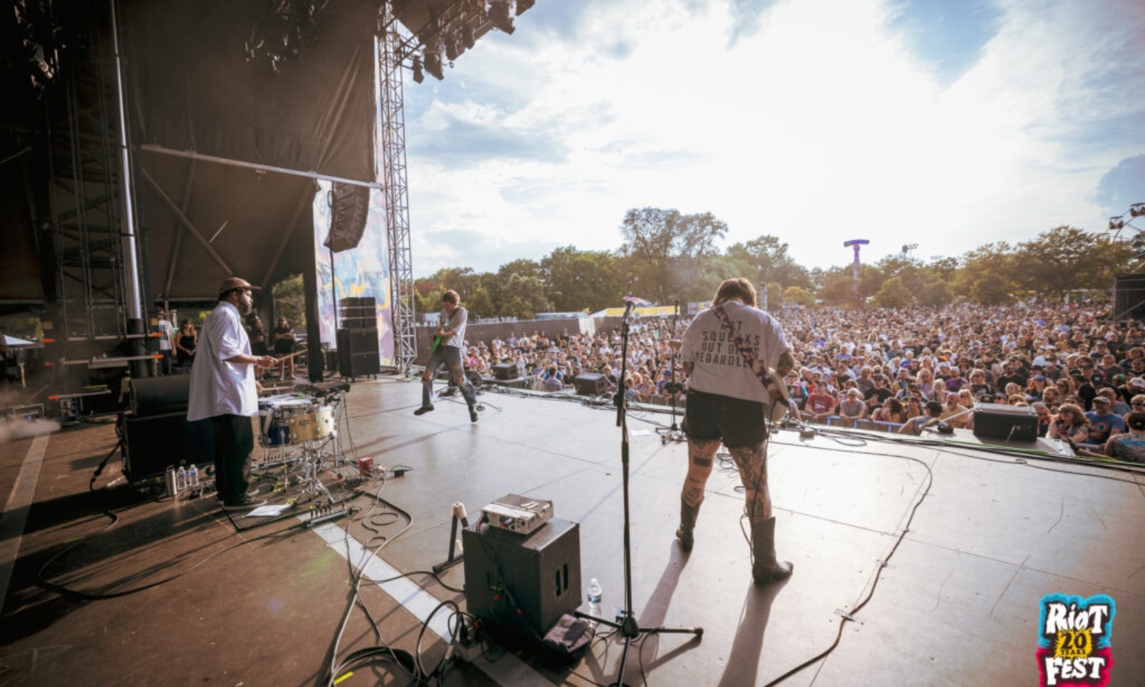 Backstage-view image of a band performing at Riot Fest in front of a crowd during the day in Chicago