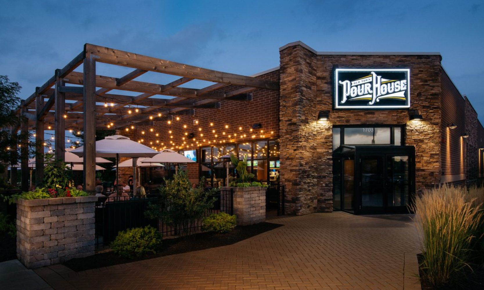 Exterior image of the Old Town Pour House building and patio dining area with hanging lights at night