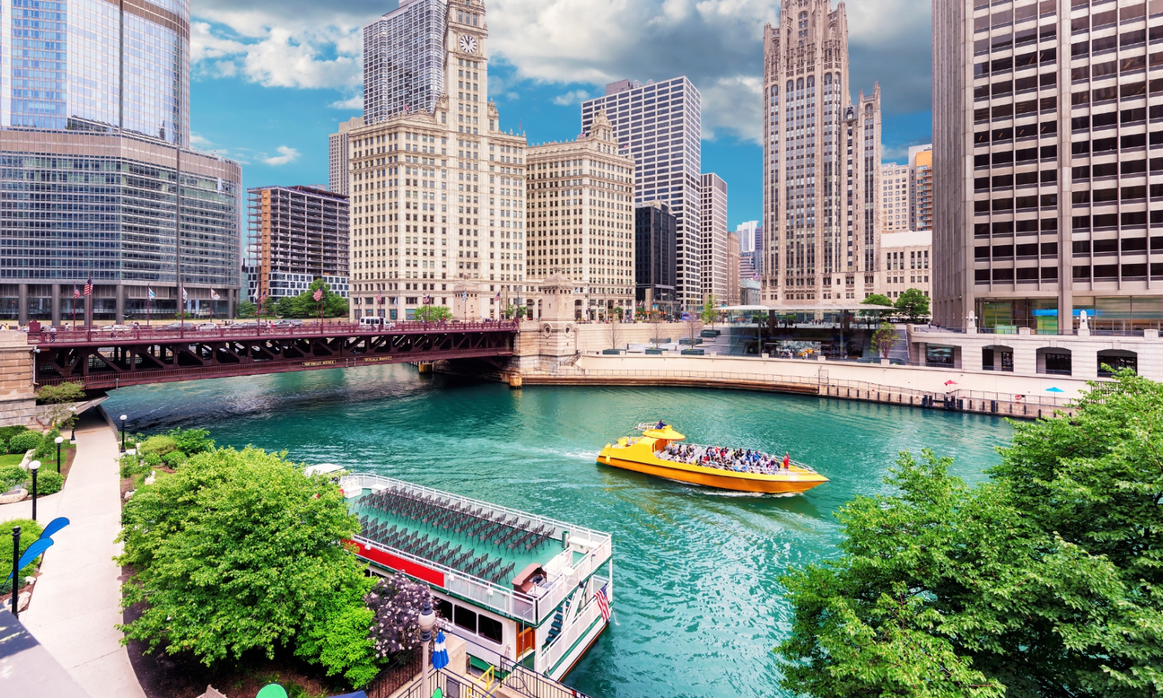 Wideshot image of a yellow boat cruising down the Chicago River in River North